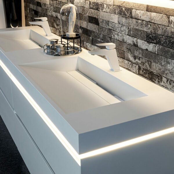 Exklusive Badmöbel: Doppelwaschtisch in den Größen 160-200-240 cm, mattes Weiß, Waschbecken aus Solid Surface Material in mattem Weiß, weiße Armaturen und moderne Beleuchtung mit Bewegungsmelder, die den Inhalt der Schubladen beleuchtet.